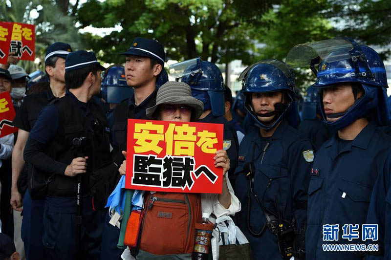 8月6日，在日本广岛原子弹爆炸遗址前，抗议民众手持标语参加集会。