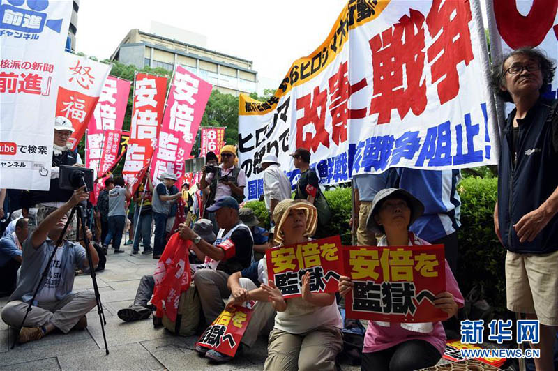 8月6日，在日本广岛原子弹爆炸遗址前，抗议民众手持标语参加集会。