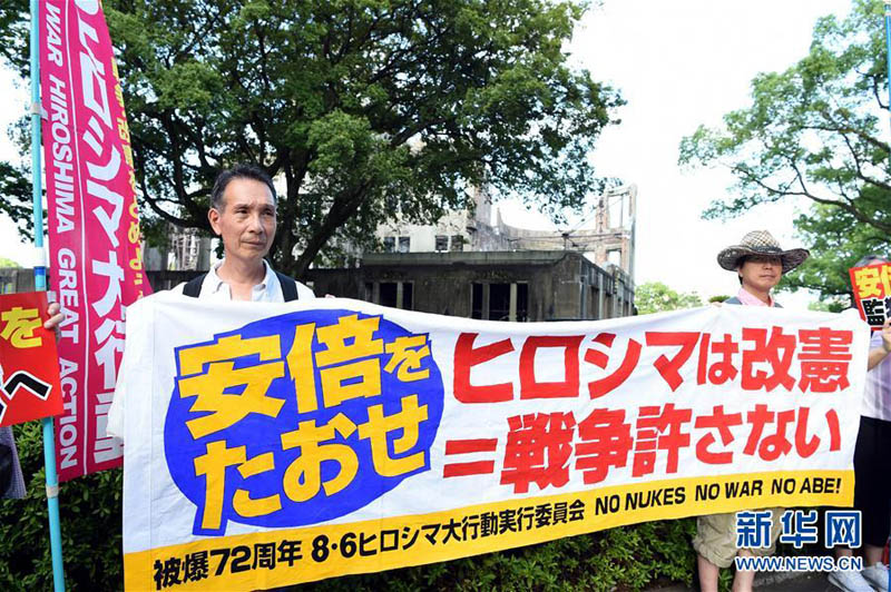 8月6日，在日本广岛原子弹爆炸遗址前，抗议民众手持标语参加集会。