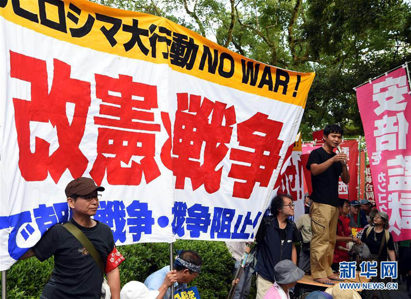 8月6日，在日本广岛原子弹爆炸遗址前，抗议民众手持标语参加集会。