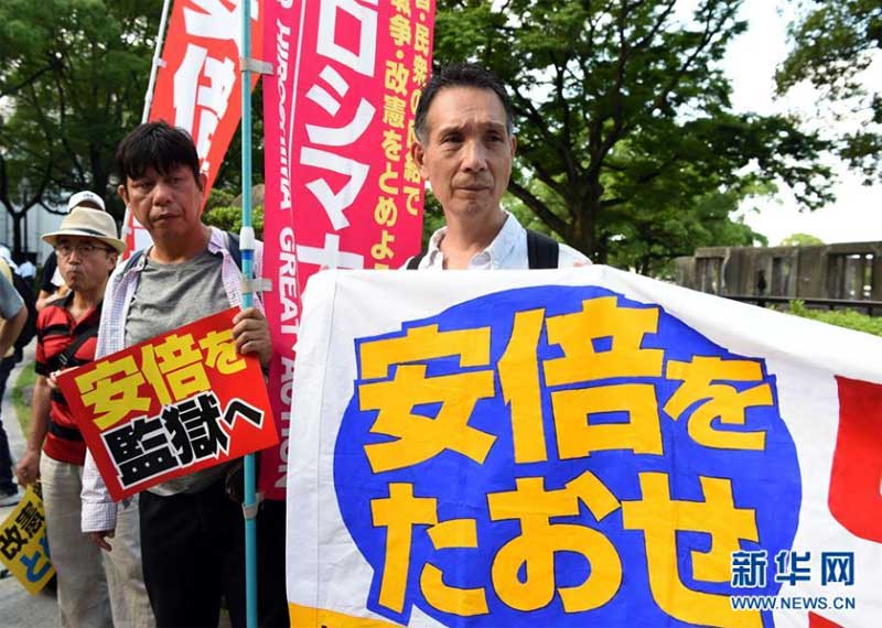 8月6日，在日本广岛原子弹爆炸遗址前，抗议民众手持标语参加集会。