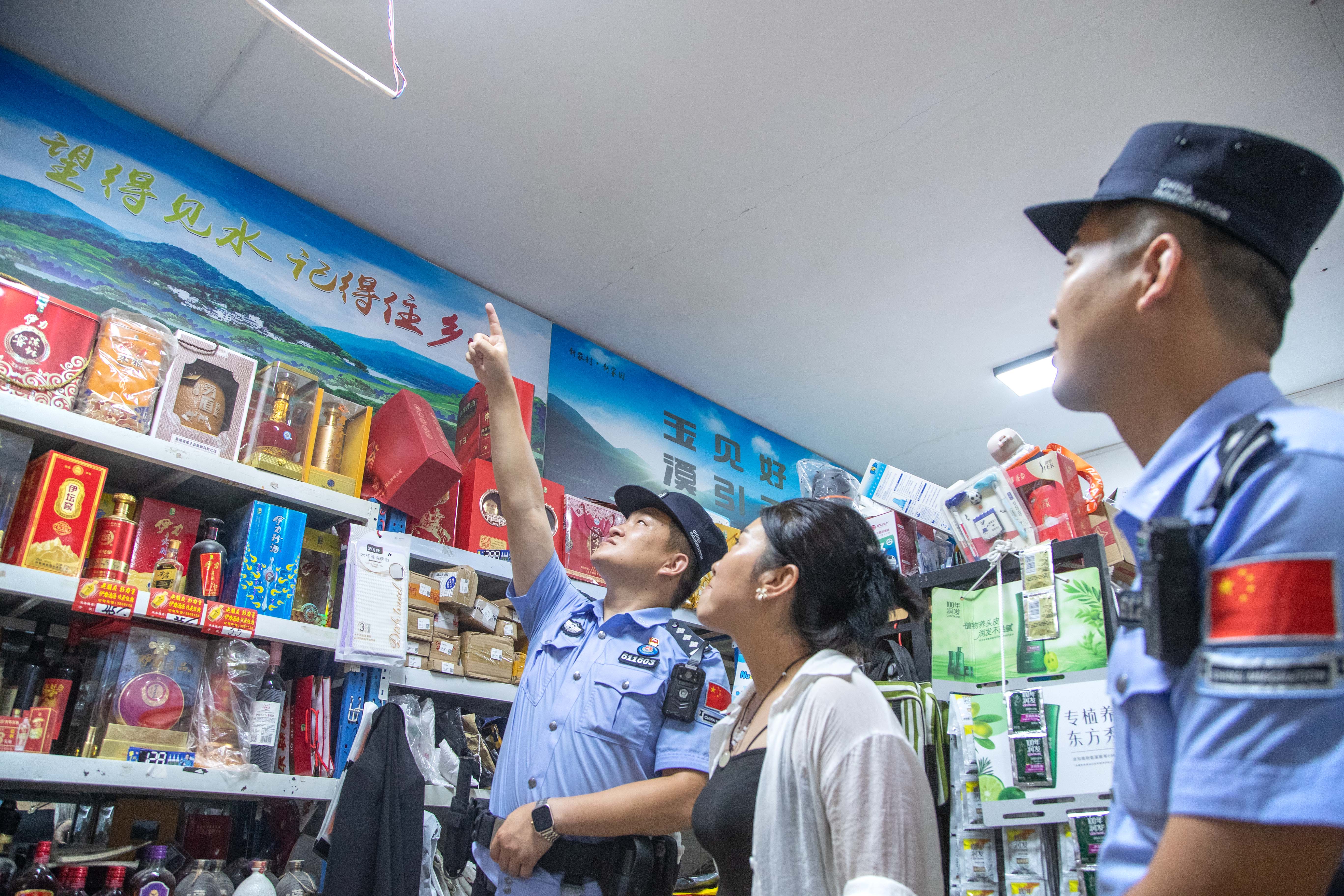 图七：8月14日晚，图为民警正在向超市老板了解经营与治安情况，并检查线路隐患。.jpg