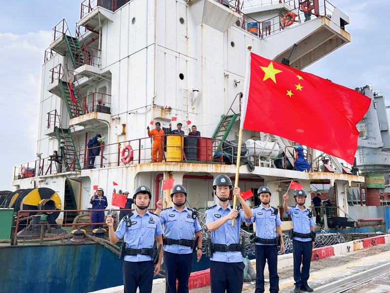 图为：莆田边检站执勤二队移民管理警察和船员与国旗合影。.jpg