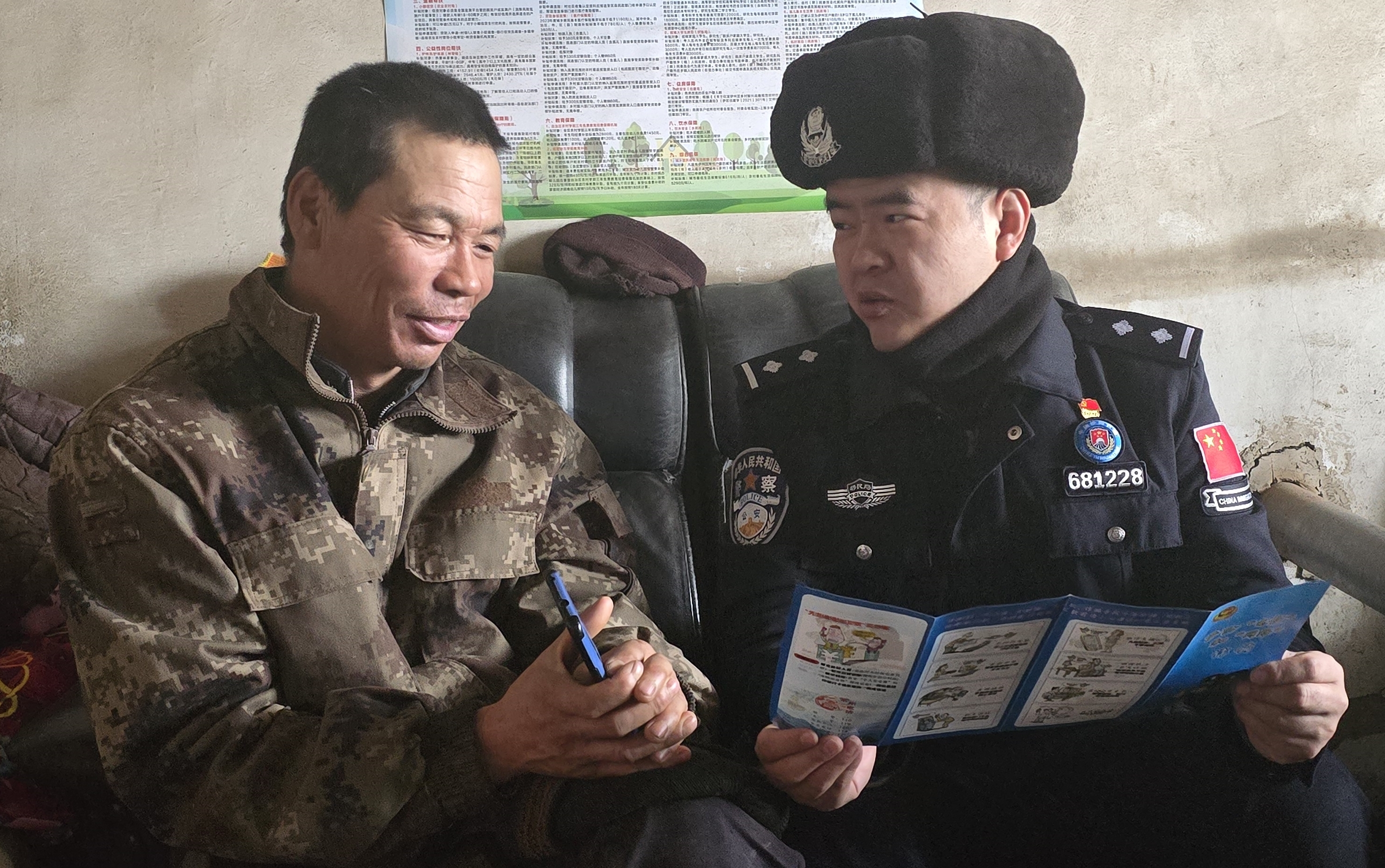 图为民警张梦豪向村民陈大哥讲解宣传手册的内容.jpg