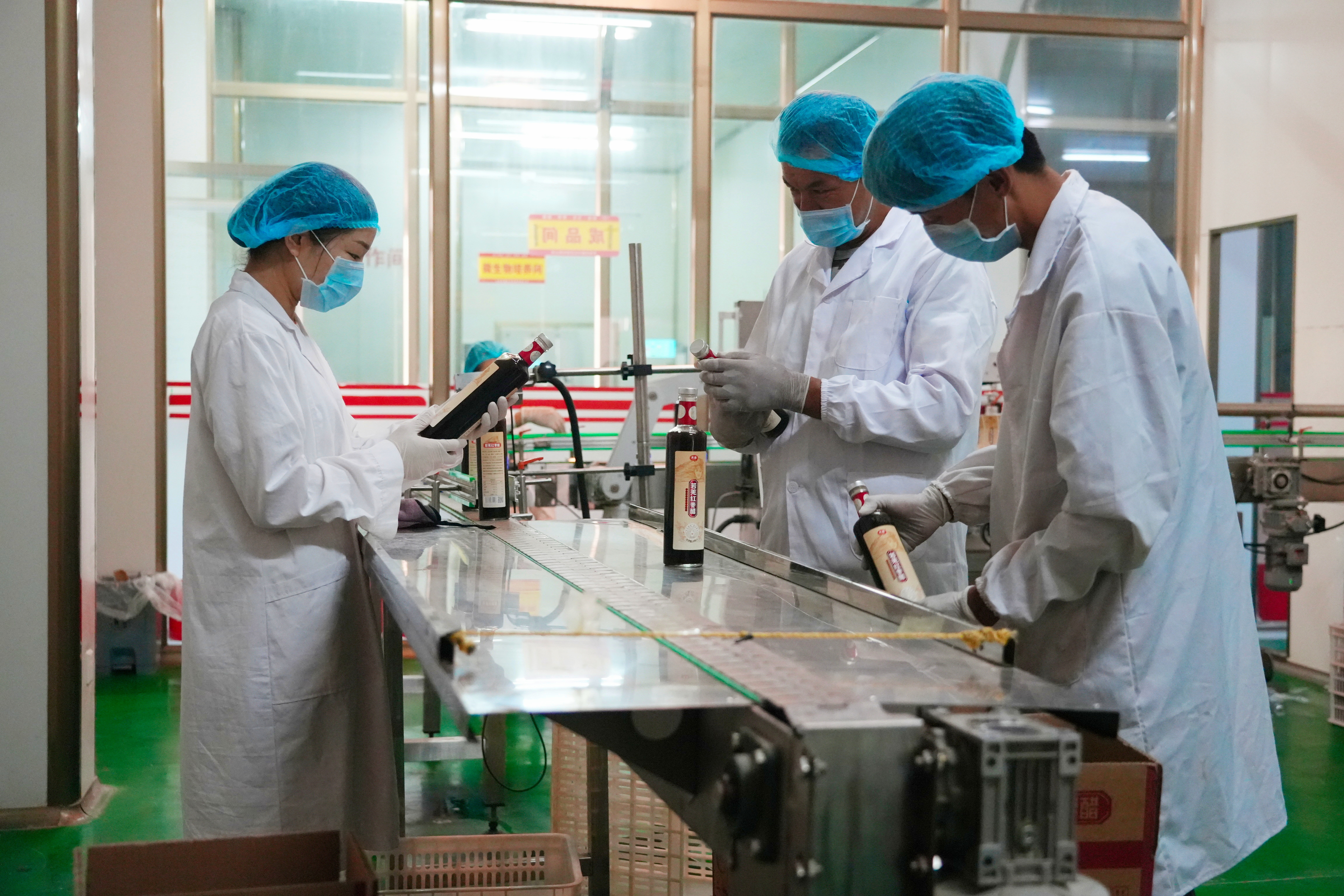 配图3：6月27日，在新疆羌域食品生物科技有限责任公司生产车间，来自吾塔木乡依孜格吾斯塘村的吾斯曼·买买提（中）和同事们正在按出厂标准仔细检查生产线传送过来的红枣醋。苏波 摄.jpg